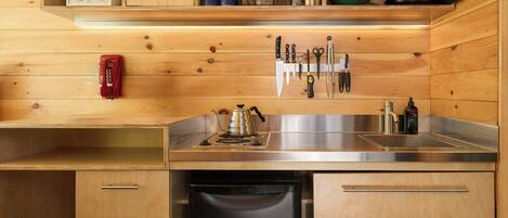 Una cocina compacta con muebles de madera, un lavamanos de acero inoxidable y un lavavajillas integrado.