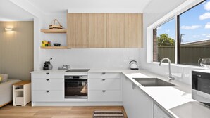 A modern kitchen with white cabinetry, a built-in oven, a sink, and a window providing a view of the outdoors.