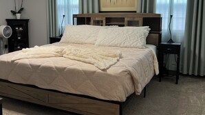 A bedroom with a large bed, a ceiling fan, a wall-mounted TV, and a window with curtains. - Sherizee Home close to beach and 3 miles to Salem's Haunted happenings (Marblehead)