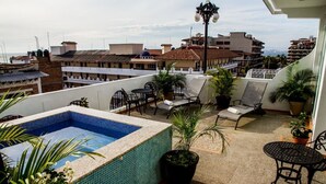 Une terrasse sur le toit avec une piscine, des chaises longues et des plantes en pot.