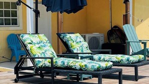Un área de piscina con dos sillas reclinables y un ventilador de techo.
