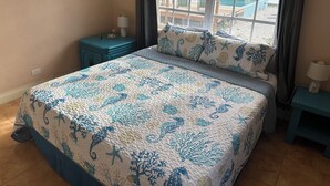 Un dormitorio con una cama, una mesita de noche, una ventana que ofrece vistas a una terraza y una pared con tres cuadros.