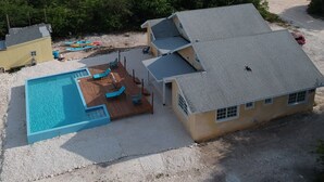 Una propiedad frente a la playa con piscina, sillas de descanso y vista al océano.
