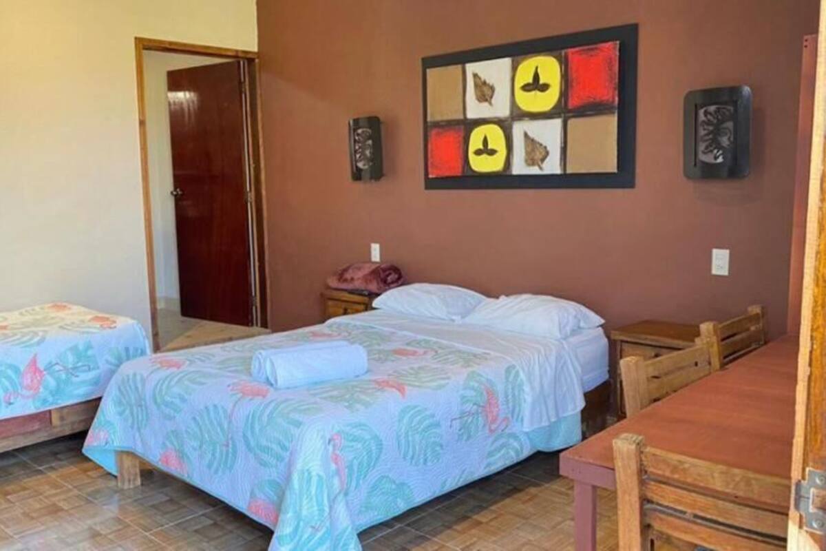 A room with two beds, a wooden table, and a door.