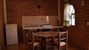 A kitchen with a brick wall, a wooden table, and four chairs.