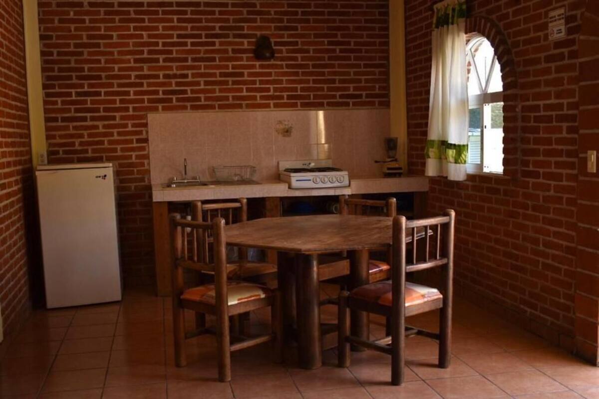 A kitchen with a brick wall, a wooden table, and four chairs.