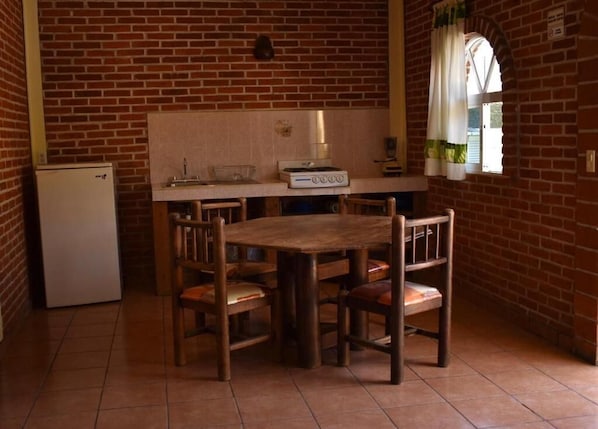 Una cocina con pared de ladrillo, mesa de madera y cuatro sillas.