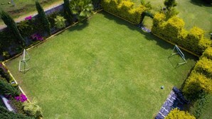 A well-maintained lawn with two swings and a stone wall.