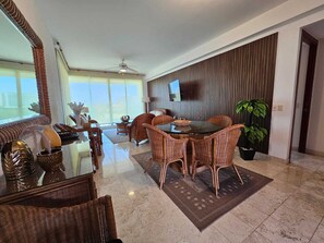 Relax in this inviting living area with a large dining table, flat-screen TV, and potted plant.
