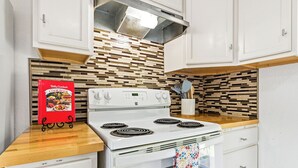 A kitchen with a white stove, a red cookbook, and a patterned towel. - Near HSU, ACU & Hendrick ~ Clean ~ Charming Cottage  ~ New Discounts ~ Dogs (Abilene)