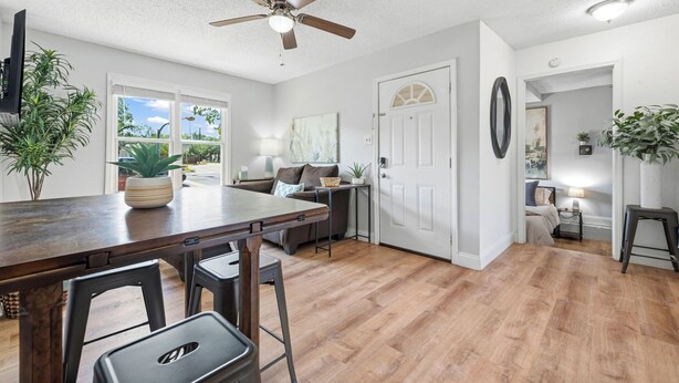 A modern kitchen with a wooden countertop, bar stools, a ceiling fan, and a view through the window. - Near HSU, ACU & Hendrick ~ Clean ~ Charming Cottage  ~ New Discounts ~ Dogs (Abilene)