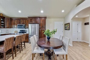 A kitchen with wooden cabinets, a stainless steel refrigerator, a microwave, and a dining table with chairs. - Timp Retreat | EV | Free Massage* | Backyard (Orem)