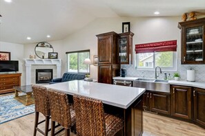 A modern kitchen with a central island, wooden cabinets, and a built-in fireplace. - Timp Retreat | EV | Free Massage* | Backyard (Orem)