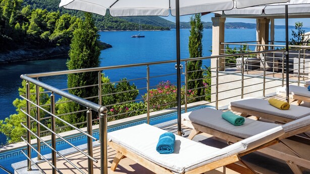 Een terras met loungestoelen en uitzicht op een meer.