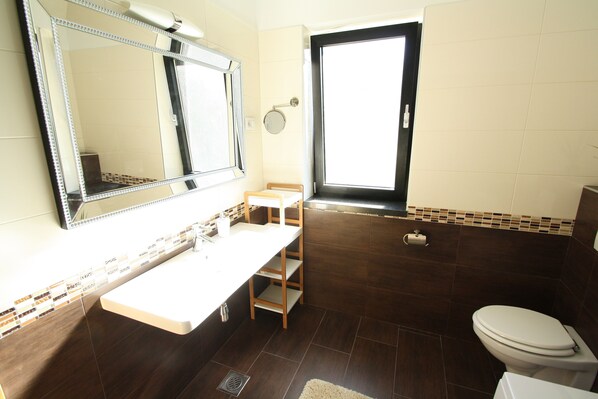 A bathroom with a large mirror, a toilet, a sink, and a window.