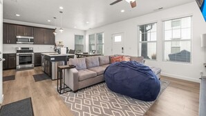 A modern kitchen with a microwave, stove, and dining area. There is a sofa and a bean bag chair in the living area.
