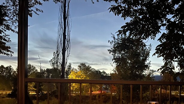 Un patio con una chimenea, una mesa de vidrio y una copa de vino.