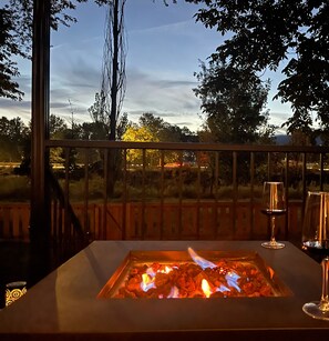 Un patio con una chimenea, una mesa de vidrio y una copa de vino.