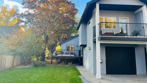 Una casa moderna de dos pisos con un porche delantero, un garaje y un gran árbol con hojas otoñales.