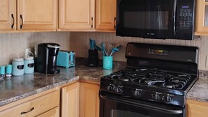 A kitchen with wooden cabinets, a black microwave, a stove, and a toaster. - Charming -Clean-4-bedroom house with AC and WiFi in wonderful Springfield (Springfield)