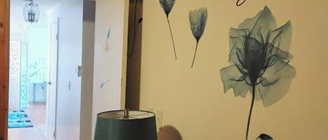 Un dormitorio con una decoración de pared que dice 'ALWAYS Kiss Me Good Night' y una lámpara sobre una mesita de noche.