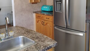 A kitchen with wooden cabinets, a stainless steel refrigerator, a sink, and a toaster. - Charming -Clean-4-bedroom house with AC and WiFi in wonderful Springfield (Springfield)
