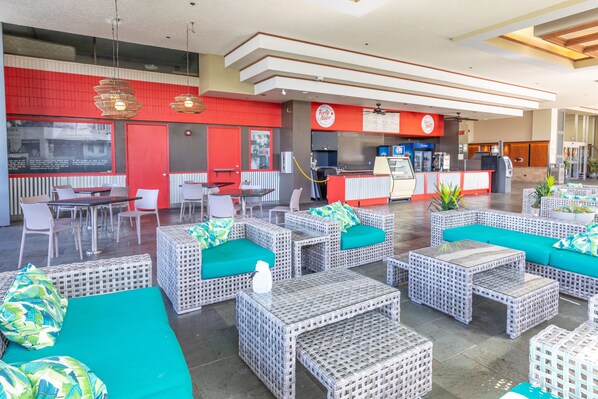 A spacious indoor area with wicker furniture and a red and white color scheme. - Ocean and City Views at Island Colony Near Waikiki Beach (Honolulu)