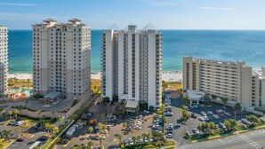 A high-rise hotel with multiple floors, a parking lot, and a view of the ocean. - Palacio 803 (Pensacola)