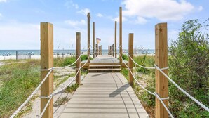 A wooden boardwalk leading to a beach with a clear sky. - Palacio 803 (Pensacola)