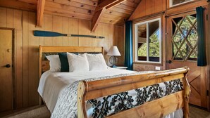 A wooden bedroom with a bed, a nightstand, and a window with curtains. - Hidden Pines - Hot Tub, BBQ & Pool Table (Big Bear Lake)