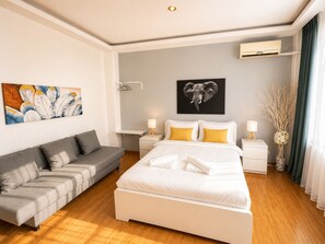 A modern hotel room with a bed, a sofa, an air conditioning unit, and a wall-mounted artwork. - Old Town Ateneu Studio (Bucharest)