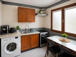 A compact kitchen with wooden cabinets, a built-in washing machine, a coffee maker, and a stove. - Old Town Ateneu Studio (Bucharest)