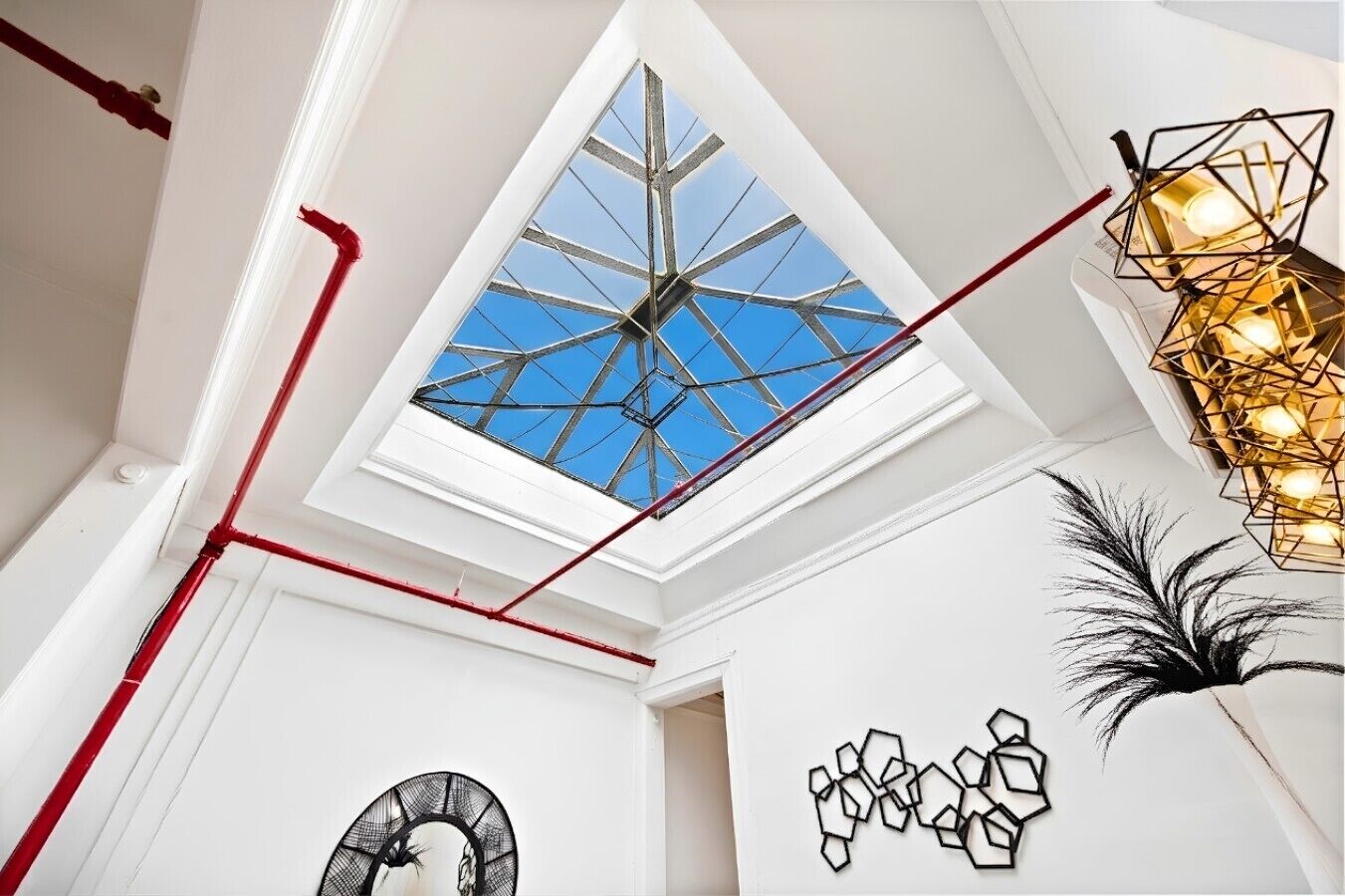 A room with a skylight, geometric wall art, and a modern light fixture.