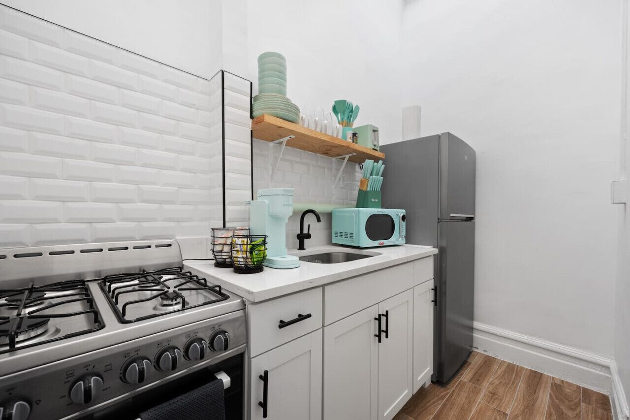A modern kitchen with white cabinets, a stainless steel stove, a microwave, and a refrigerator.