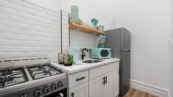 A modern kitchen with white cabinets, a stainless steel stove, a microwave, and a refrigerator.