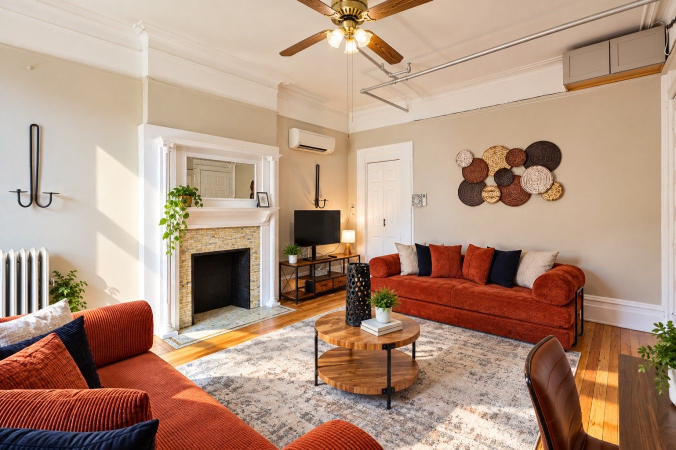 A living room with a fireplace, a sofa set, a TV, and a ceiling fan.