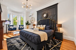 A bedroom with a large bed, a TV, a desk, and a chair.
