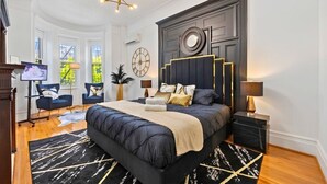 Ein Schlafzimmer mit einem großen Bett, einem Fernseher, einem Sessel und einem Schreibtisch.