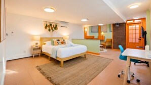 Un dormitorio con cama, mesitas de noche, escritorio y silla.