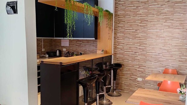 A modern kitchen with a central island, bar stools, and a dining area with orange chairs. - kallma adventures (Ica)
