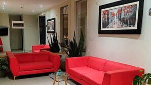 A living room with two red sofas, a glass coffee table, and a framed picture on the wall. - kallma adventures (Ica)