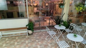A balcony with a checkered floor, white metal chairs, and tables, surrounded by potted plants. - kallma adventures (Ica)