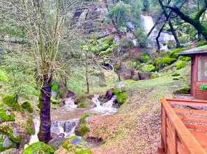 Une cabane en bois avec une petite cascade en arrière-plan.