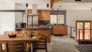 A modern kitchen with a central island, wooden cabinetry, and a stone floor.