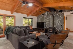 Un salon moderne avec une cheminée en pierre, un canapé, un téléviseur et une table basse.