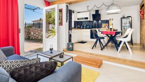 A modern living room with a sofa, coffee table, and a dining area with a table and chairs.