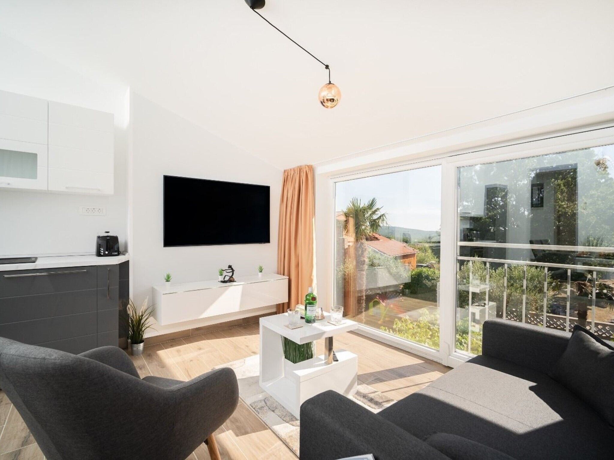 A modern living room with a sofa, a coffee table, and a TV mounted on the wall.