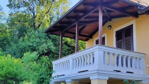 A two-story building with a balcony, surrounded by lush greenery.
