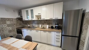 A modern kitchen with white cabinets, a stainless steel refrigerator, and a wooden countertop.