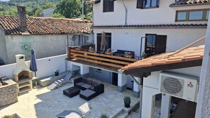 Eine großzügige Außenpatio mit Grill, Sitzgelegenheit und Blick auf eine hügelige Landschaft.